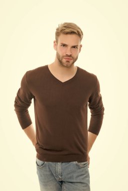 Karizmatik adamın modaya uygun bir saç stili var. Beyaz giyinmiş, erkek giyim tarzında günlük kıyafetler giyiyor.