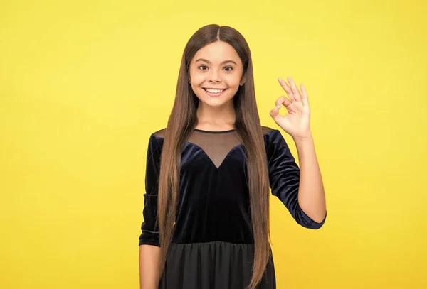 Ευτυχισμένο θηλυκό παιδί με ομορφιά ματιά στο φόρεμα μόδας δείχνουν ok τραγουδούν χέρι χειρονομία κίτρινο φόντο, κορίτσι — Φωτογραφία Αρχείου