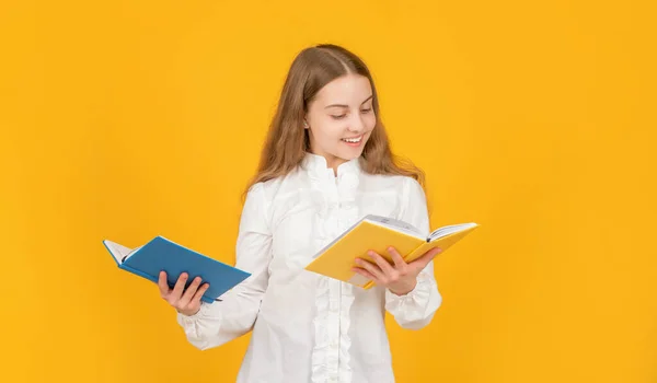 Chytré dítě v bílé košili připraven ke studiu domácí úkol s knihou na žlutém pozadí, knihomol — Stock fotografie