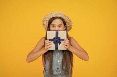 Kendi kutunu tasarla. Küçük kız hediye kutusunu sarı arka planda tutuyor. Tatil kutlaması. Doğum günü yıldönümü. Paket mi paket mi? Hediyelik eşya dükkanı. Alışverişe. Teslimat hazır. Kurdeleyi kutunun etrafına bağla