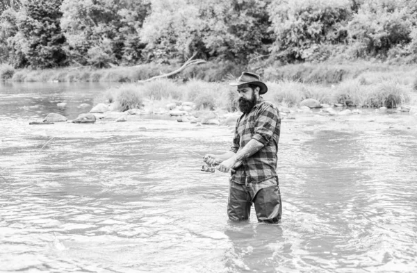 Satisfied fisher. Fisher masculine hobby. Fisher fishing equipment. Fish on hook. Fishing requires you to be mindful and fully present in moment. Brutal man wear rubber boots stand in river water — Stock Photo, Image