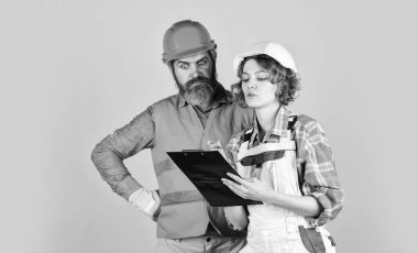 Yenileme konsepti. Müteahhitle tadilat hakkında konuşuyorduk. Çift planlama yenileme dairesini değiştirir. Kadın ve erkek güvenlik kaskı. Yuvanın yenilenmesi. Çift evraklara bakıyor. Kontrol süreci