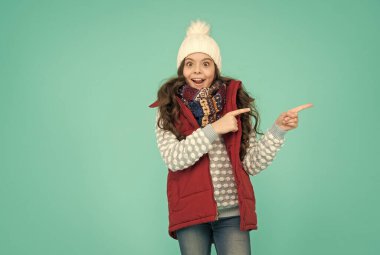 Orada xmas indirimi var. Yeni yıl tatiline hazırım. Hipotermi yok. Neşeli kız kıyafet katmanları giyer. Kış mevsiminde kalın giysiler. Soğuk hava tahmini. Çocuk moda alışverişi. işaret parmağı