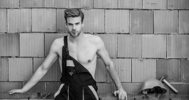 Seksi işçi seni. Çekici bir işçi. Yakışıklı adam tulum giyer. İnşaat. İşçi tuğlası duvar arka planı. Temel görevleri yerine getir. Erkeklik kavramı. Genel bakım işçisi. Dinlenmek için mola