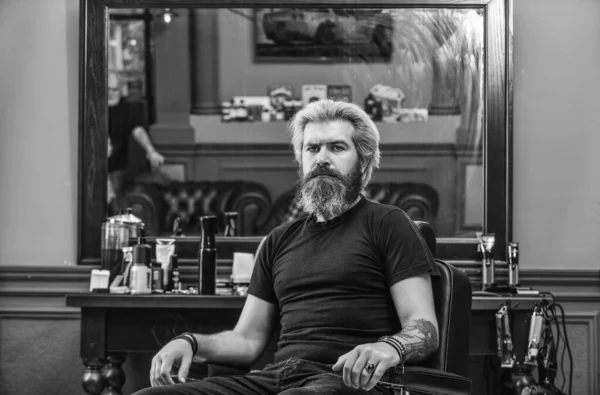 Style yourself. Time for new haircut. man look at mirror reflection. mature handsome man with long hair. barber or hairdresser tool. brutal hipster at barbershop. bearded client visiting hairdresser