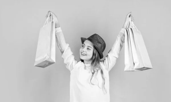 Niño feliz sostiene bolsas de la compra. look de moda vintage. colección de accesorios de verano. niño pequeño pelo largo. adicto a las compras de belleza. paquetes de cuidado de los compradores de niños. chica retro fondo azul — Foto de Stock