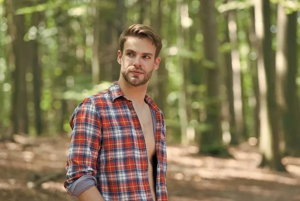 Schöner Typ mit unrasiertem Gesicht trägt offenes kariertes Hemd in sommerlicher Natur, lässig — Stockfoto