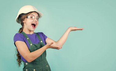 Çocuk kaskla çalışıyor. Kasklı küçük kız. Tamir yapan bir kız. Başlık takmış bir genç. Çocukluk gelişimi. Miğferli kız inşaat işçisi. Ustabaşı ergen çocuk. ürün sunuluyor