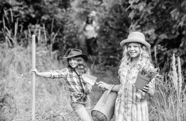 Siostry pomagające na farmie. Koncepcja rolnictwa ekologicznego. Urocze dziewczyny w kapeluszach sadzące rośliny. Rodzeństwo bawi się na farmie. W drodze na rodzinną farmę. Zajmuję się roślinami. Dziewczyny z narzędziami ogrodniczymi — Zdjęcie stockowe