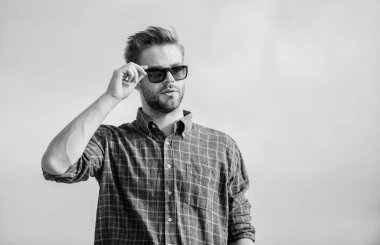 Net olarak gör. Yakışıklı adam güneş gözlüğü takıyor. Moda güneş gözlüklü hippi. Modaya uygun güneş gözlükleri. Ultraviyole koruma kavramı. Erkek gözlüklü model açık havada mavi gökyüzü arka planı. Mükemmel görüş