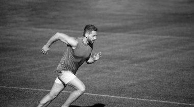 Enerjik atletik kaslı adam koşucu yeşil çimlerin üzerinde koşuyor, kopyalama alanı, başarı