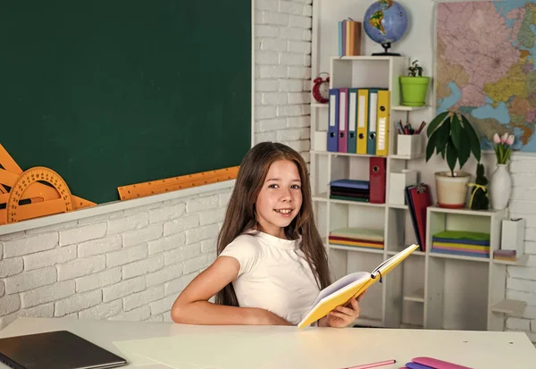 4.微笑的少女在学校的教室里看书 — 图库照片