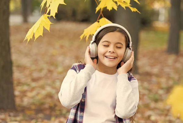 秋のベスト・ソング。可愛い小さな子供はヘッドフォンで演奏する歌を楽しむ。愛らしい少女が歌に合わせて歌う。秋は歌を残す。音楽と韻 — ストック写真