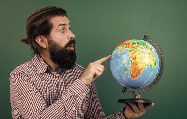 Kareli gömlekli sakallı adam coğrafya, coğrafya okulu eğitimine bakıyor.