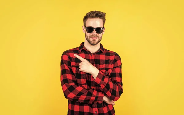 Puntando il dito. concetto di barbiere. Gli uomini indossano. giovane bel ragazzo in camicia a scacchi e occhiali. elegante uomo indossare abiti casual. uomo barbuto con setole sul viso non rasato. moda e bellezza — Foto Stock