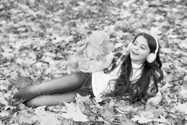 Lugar perfeito para ficar. criança relaxar na floresta de outono. folhas de bordo queda no parque. felicidade infantil. beleza e natureza. O miúdo feliz usa auscultadores. menina adolescente ouvir música no caminho para a escola — Fotografia de Stock