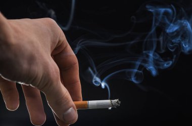 Erkek eli dumanlı sigara dumanı arka planda, sigara içiyor.