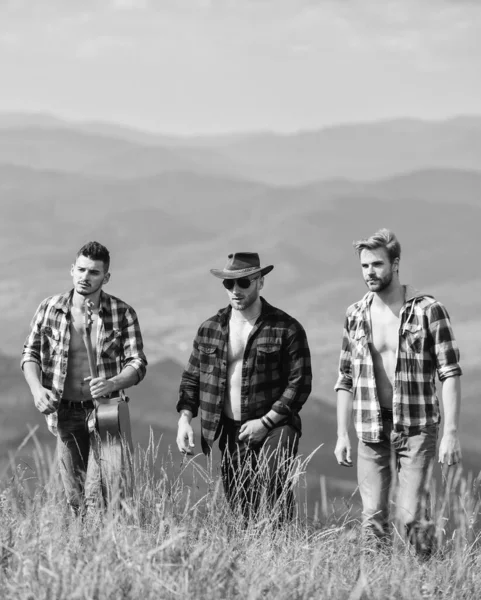 Face à la musique. camping à l'ouest. chansons de feu de camp. aventure de randonnée. des cow-boys. hommes heureux amis avec guitare. amitié. hommes avec guitare en chemise à carreaux. groupe de personnes passent du temps libre ensemble — Photo