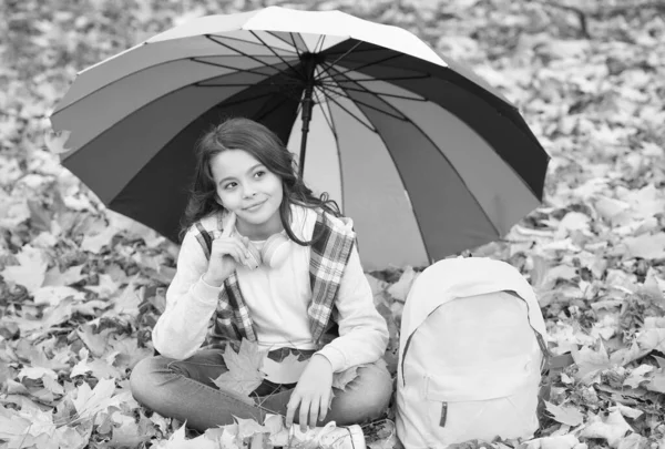 Bambino felice in stile casual trascorrere il tempo di relax nel parco autunnale godendo di bel tempo sotto ombrello colorato, umore ottimista — Foto Stock