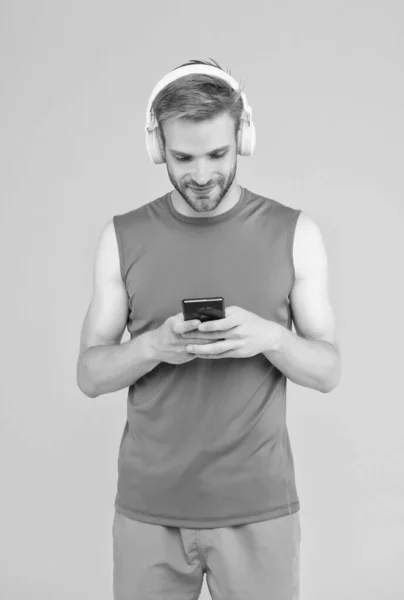 Homme barbu joyeux écouter de la musique dans les écouteurs numériques en utilisant l'application de téléphone mobile portant des vêtements sportifs pour l'entraînement, réseau social — Photo