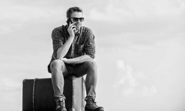 Seyahat etmeyi kabul et. Gözlüklü iş adamı. İş gezisi. Maço turist rahat tur çantası. Erkek modası. Çok modaya uygun görünüyorsun. Seksi adam gökyüzü arka planı telefonda konuşuyor. Gezgin, taksi bekle. Taşı