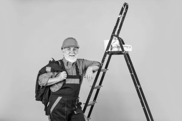 Trabajos de aislamiento térmico. Escalera de hombre pintor. Para hacer reparaciones. hombre en ropa de trabajo pintando pared en habitación vacía. pintor en general y tapa con cubo de pintura. constructor trabajador pintura fachada —  Fotos de Stock