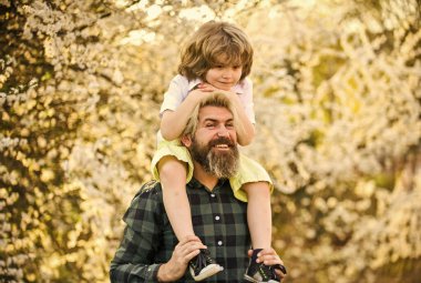 Birlikte eğleniyoruz. Aşk konsepti. Neşeli baba parkta çocukla oynuyor. Küçük tatlı oğlu olan yakışıklı bir baba. Çiçek ve doğanın tadını çıkarın. Mutlu aile günleri. Bahar geliyor. Eğlenmene bak.