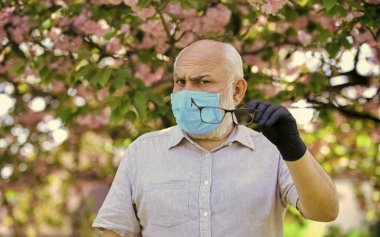 Salgın sırasında önlemlere dikkat edin. sağlıklı bir hayat. Çiçek açan pembe sakura parkında maske takın. Sakura 'daki koruyucu maskeli adam. Koronavirüs karantinasında çiçek kokusu alıyorum.