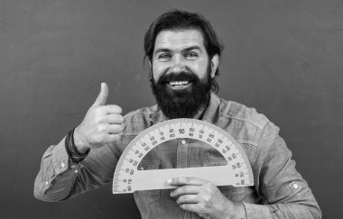 Olgun sakallı erkek öğretmen. Okulda tahtası ve matematiği olan bir öğretmen.