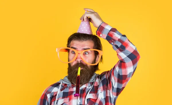 Con uno sguardo buffo. l'uomo barbuto festeggia la festa. anniversario. sorpresa per lui. event manager con regalo. ragazzo maturo in camicia a scacchi con cappello da festa. maschio elegante divertirsi il compleanno — Foto Stock