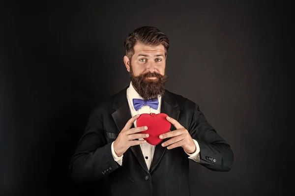 Hombre guapo en esmoquin sosteniendo regalo de amor de corazón para el día de San Valentín, San Valentín —  Fotos de Stock