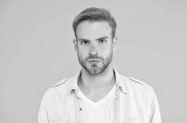 Tıraşsız, tüylü yakışıklı bir adam. Erkek yaz modası. Ciddi adamın sarı arka planda saçları var. İnsani duygular. Havalı saç stili olan seksi çocuk gömlek giyiyor.