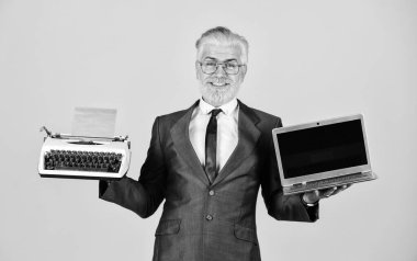 Uzaktan eğitim. Modern dijital iş. Klasik daktilo. Başarılı iş adamı retro daktilo ve modern laptop. Olgun bir adam sakal boyadı. Bilgisayar ya da daktilo. yeni ve eski teknoloji