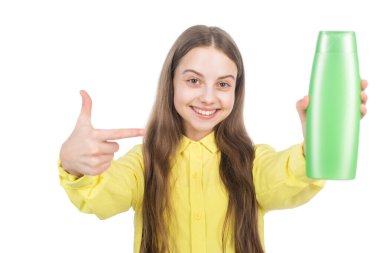 Mutlu çocuk, şampuanı ya da saç kremi şişesini işaret ediyor. Beyazın üstünde izole edilmiş.