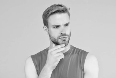 Kendi tarzında. Saçları taranmış ciddi bir adam. Erkek güzellik standardı. Sarı arka planda sıradan bir adam. Berber dükkanı konsepti. Spor ve spor modası. Tüylü yakışıklı genç adam.