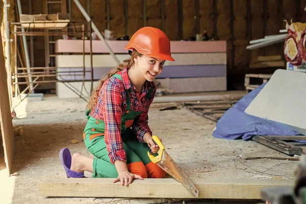 girl working with wood in workshop. carpentry and woodwork concept. Portrait of a cute kid posing as a carpenter, with a handsaw. working as woodworker. carpenter in protective hat work