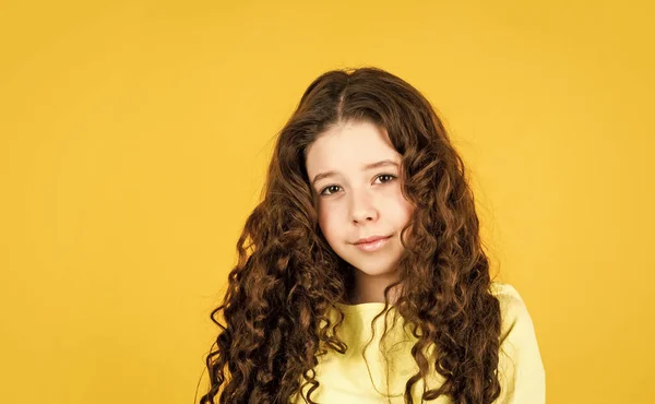 Cabello largo. Peinado fácil. Artículos de belleza. Desenreda perfectamente el cabello rizado. Chica bonita pelo rizado fondo amarillo. Peluquería. Adorable niño pequeño. Hermosa modelo. Rizos saludables — Foto de Stock