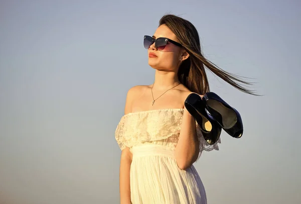 Afterparty concept. Woman sunrise carry high heels in hand. Woman on sunny morning blue sky. Model tender summer dress. Freedom. Summer holidays. Girl in sunglasses copy space. Towards summer — Stock Photo, Image