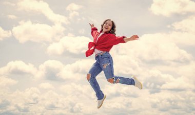 Hayal gücünü serbest bırak. Çocuk güzelliği ve moda. Sıradan bir şekilde çocuk atlayışı. Çocuk gökyüzünün arka planında zıplıyor. Yaz tatili konsepti. çocukluk mutluluğu. Mutlu Çocuklar Günü