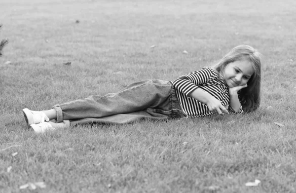 Nettes kleines Kind trägt lässige Mode Stil liegend auf grünem Gras natürliche Landschaft, Sommer — Stockfoto