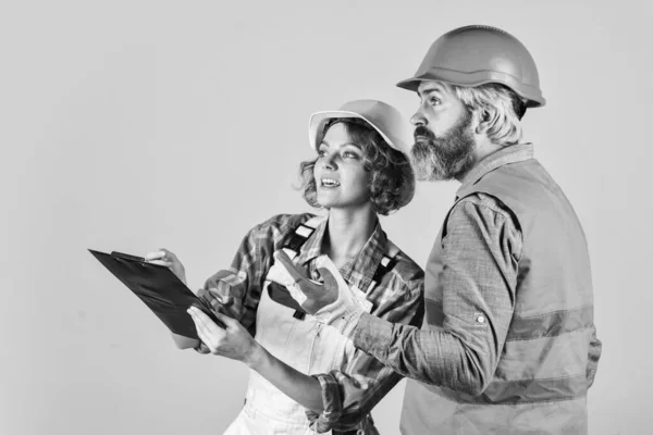 Mujer y hombre de seguridad sombrero duro. Discutiendo renovación con el contratista. Reurbanización del hogar. Un par de documentos. Pareja de planificación cambia apartamento de renovación. Proceso de control. Concepto de renovación —  Fotos de Stock