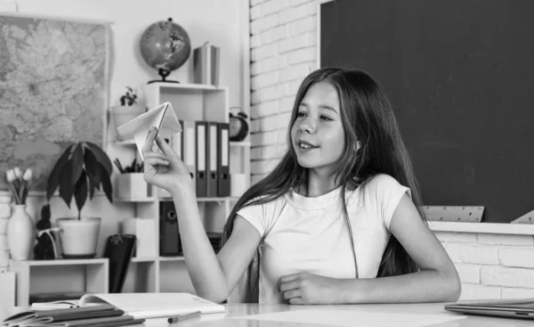 Com humor brincalhão. menina é estudante universitário. de volta à escola. menina adolescente trabalhar em sala de aula perto de quadro-negro. criança alegre aprendendo assunto. educação moderna. Dia do conhecimento. aluno criança sente-se à mesa — Fotografia de Stock