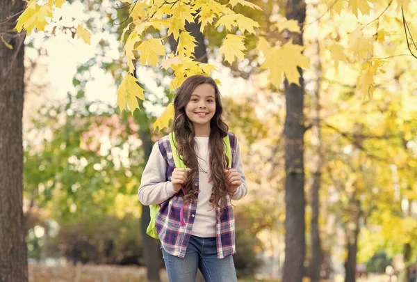 Boldog gyerek viseljen alkalmi stílust. A tinédzser lány hátizsákot hord az iskolába menet. gyermek séta őszi erdőben. őszi levelek a parkban. szezonális időjárás. Gyerekkori boldogság. szépség és természet — Stock Fotó