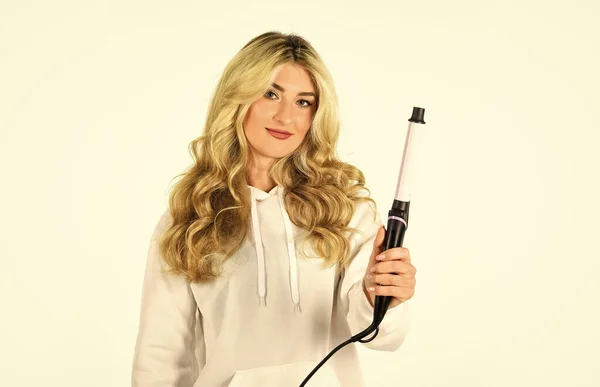 Girl adorable blonde hold curling iron white background. Form exquisite curls and romantic light waves. Woman with long curly hair use curling iron. Hairdresser equipment. Heat setting for hair type