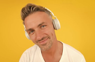 Dikkatle dinliyor musun? Orta yaşlı bir adam kulaklık takıyor. İngilizce okulu. Yabancı dil öğreniyorum. Ses kursları. Dinleme alıştırması. Modern eğitim. Dinle teknoloji