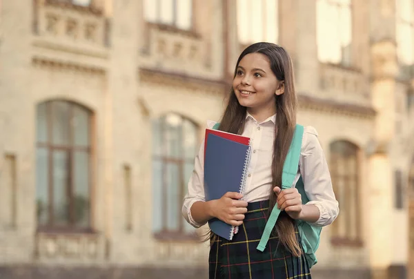 Mała dziewczynka student szkolny mundur i plecak trzymać książki, w kierunku koncepcji sukcesu — Zdjęcie stockowe
