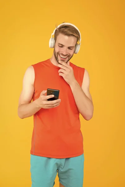 Sportsman guy with headphone and smartphone. male fitness style. man in headset listen song for training. sport and music. playlist on mp3 player. innovative wireless device. workout. shopping online — Stock Photo, Image