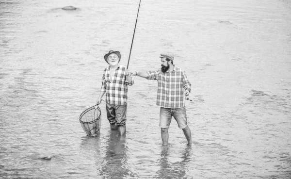 work as a team. rural getaway. hobby. wild nature. two happy fisherman with fishing rod and net. Camping on the shore of lake. father and son fishing. Poaching. Big game fishing. friendship