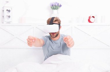 Oyun devam ediyor. Oyun geliştiricisi veya oyuncu. Video oyunu için Vr gözlüğü takan yakışıklı adam. Sanal gerçeklik kulaklık ile Kafkas adam yatakta pc oyunu oynarken zevk