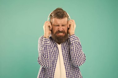 Sesi kıs. Mutsuz hipster dinleme kitabı. Kulaklıkta yüksek sesle konuşan sakallı adam..